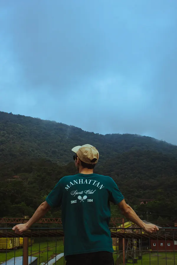 Rapaz de costas olhando para a serra coberta de mata