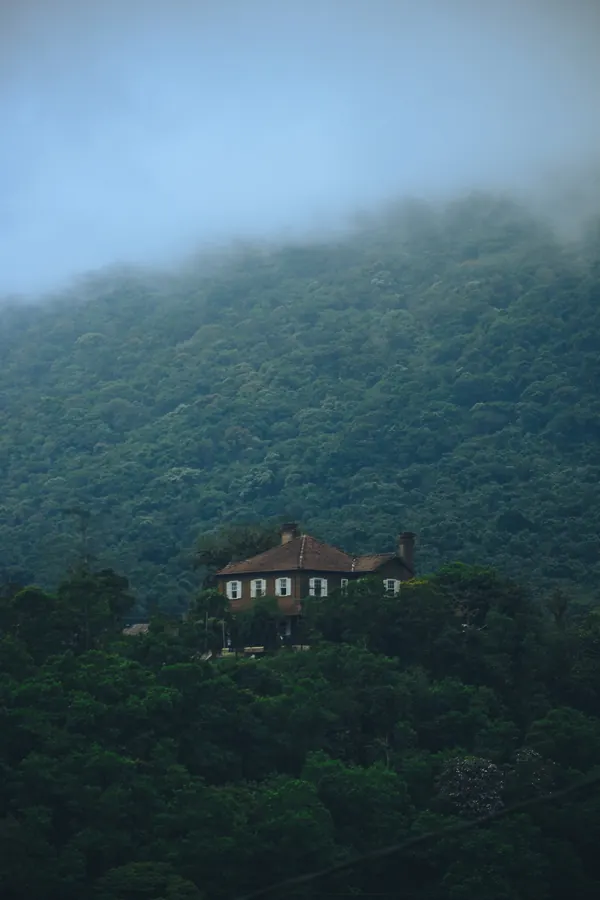 Casa isolada na encosta de uma serra encoberta pela neblina